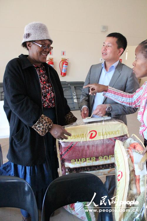 自由州省福建同乡会会长石欣平在向贫困老人捐赠生活用品。(依拉 摄)